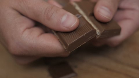 Person breaking a chocolate bar into small pieces for microdosing